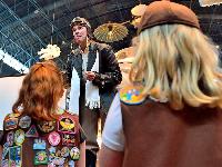 Woman in aviator costume talks to girls in girl scout vests