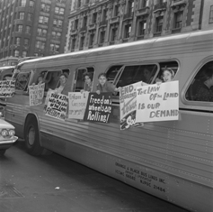 Freedom Riders hang posters from a bus.